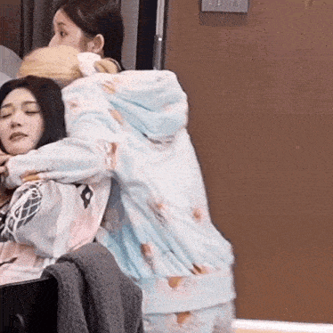 a woman is hugging another woman in front of a wooden door .