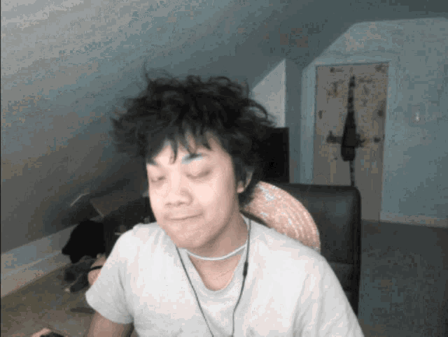 a man wearing a white shirt and a choker is sitting in a chair