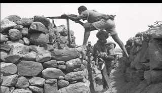 a black and white photo of soldiers in a rocky area