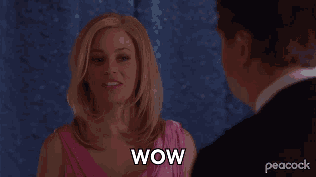 a woman in a pink dress says wow in front of a peacock logo