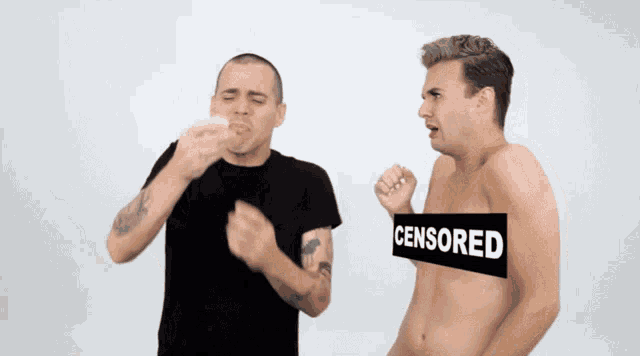 a shirtless man stands next to another shirtless man with a censored sign covering his chest