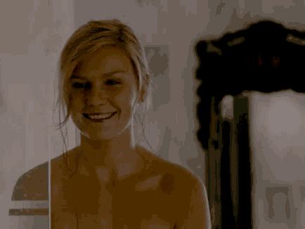 a naked woman is smiling in front of a sign that says fiquei sem graca