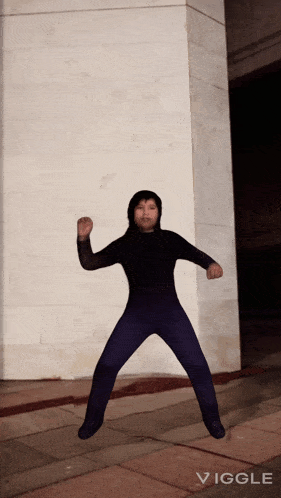 a person in a black suit is jumping in front of a wall with the word vigge below them