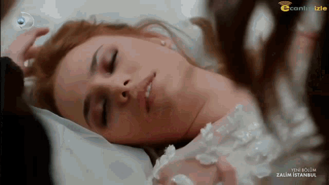 a woman in a white dress is laying on a bed with the words yeni bolum zalim istanbul on the screen