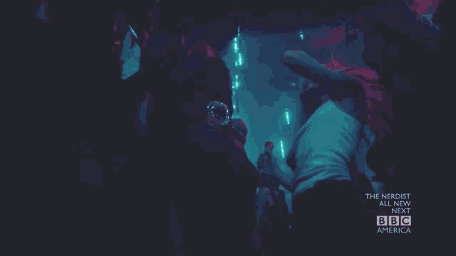 a group of people are dancing in front of a sign that says the nerdist all new next