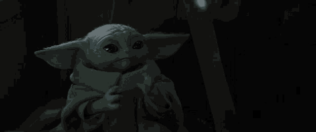 a baby yoda from star wars is sitting in a chair and making a face .