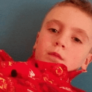 a young boy is taking a selfie with a red jacket on .