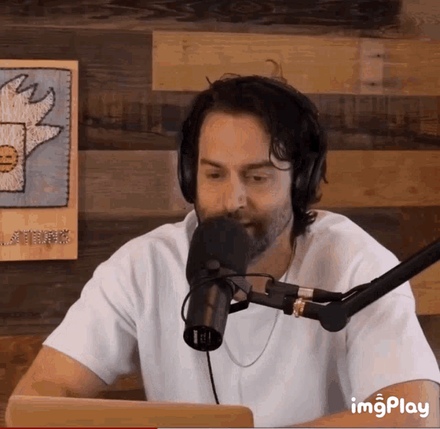 a man wearing headphones talking into a microphone with imgplay written below him