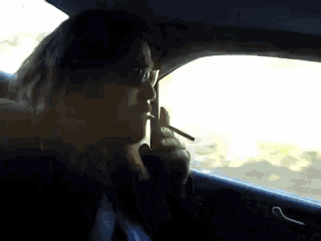 a man is smoking a cigarette in a car .