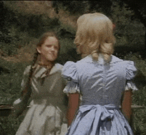 two girls in blue dresses are standing next to each other in the grass .