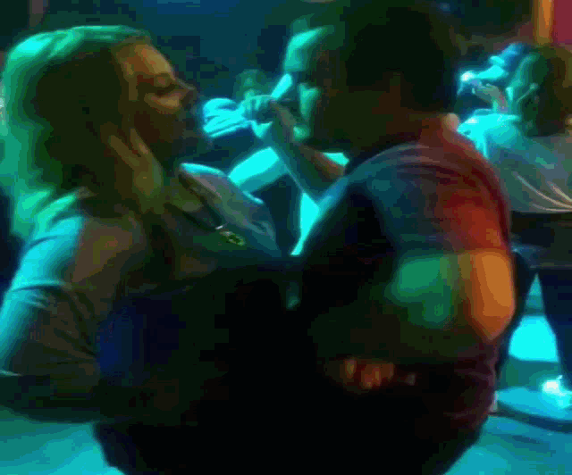 a woman is laying on a man 's back in a dark room