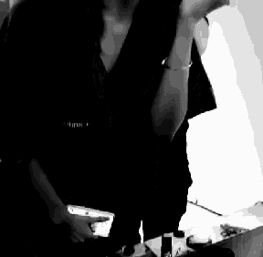 a black and white photo of a woman applying makeup with a brush