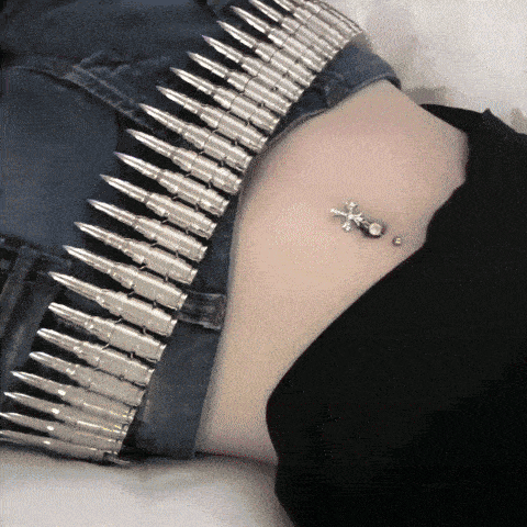 a woman with a bullet belt around her waist has a belly button piercing