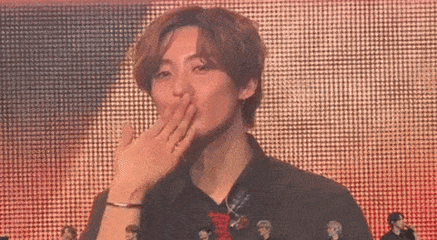 a young man is covering his mouth with his hand while standing on a stage .