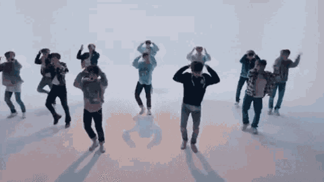 a group of young men are dancing together in a room in front of a white background .