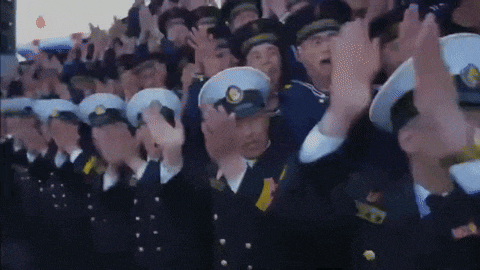 a large group of military men are standing in a line with their hands up in the air .