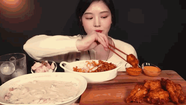 a woman is eating fried chicken with chopsticks and a bowl of rice