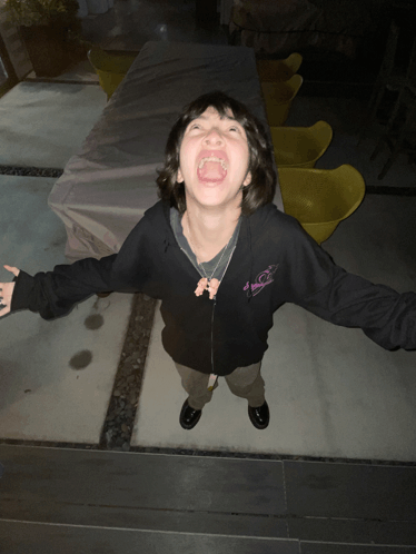 a young boy wearing a black hoodie with a pink butterfly on the front is making a funny face