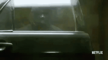 a man is sitting in the driver 's seat of a car in a garage .