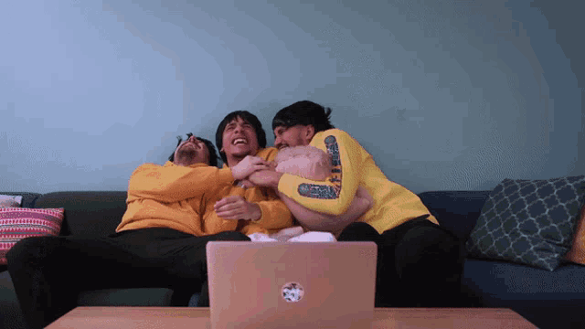 three men are sitting on a couch with one wearing a yellow sweatshirt that says ' dirty '