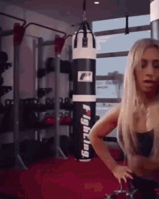a woman is standing in a gym next to a punching bag .
