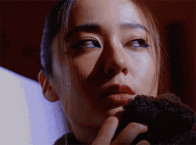 a close up of a woman 's face with a hand on her chin