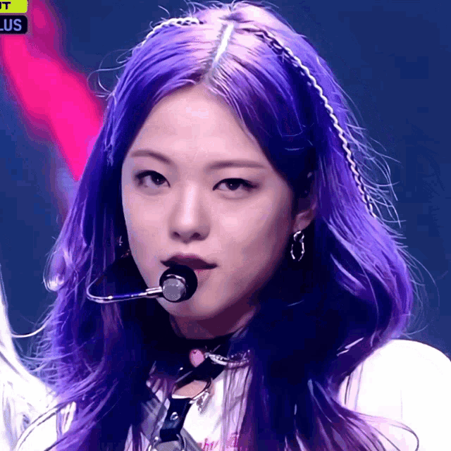 a woman with purple hair is wearing a microphone