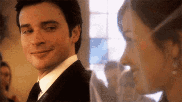 a man in a suit and tie is smiling next to a woman in a white shirt .