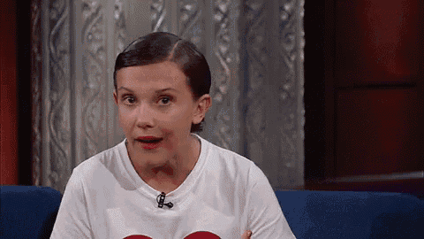 a young woman is sitting on a blue couch wearing a white t-shirt with a microphone on it .