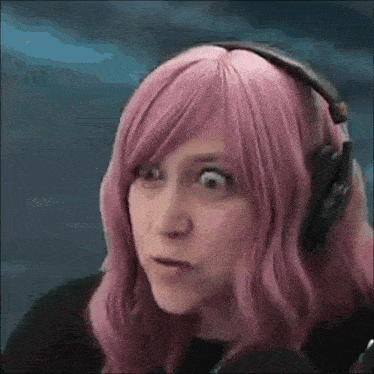 a woman with pink hair and headphones making a funny face .