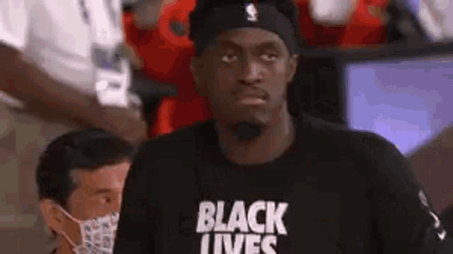 a man wearing a black t-shirt that says `` black lives '' is standing in the stands .