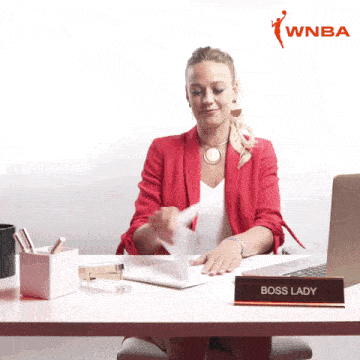 a woman sits at a desk with a sign that says boss lady on it