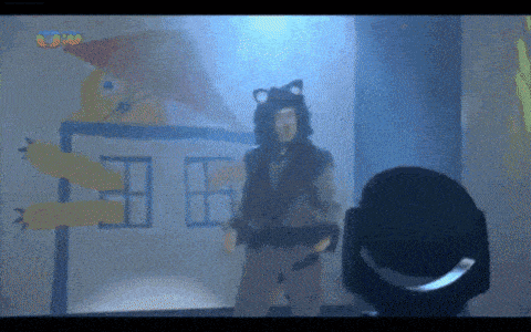 a man in a cat costume is standing in front of a spotlight and a drawing of a house