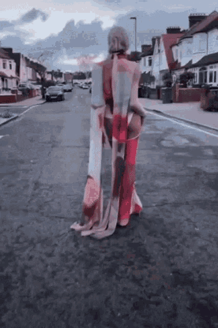 a woman is walking down a street with a blanket covering her entire body