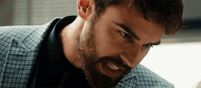 a close up of a man with a beard wearing a plaid suit