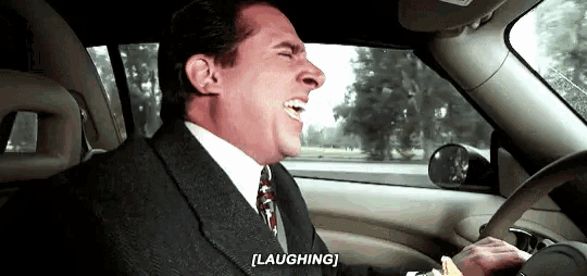 a man in a suit and tie is laughing in a car .
