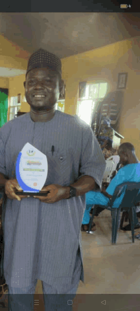 a man in a gray shirt is holding a plaque that says nigeria