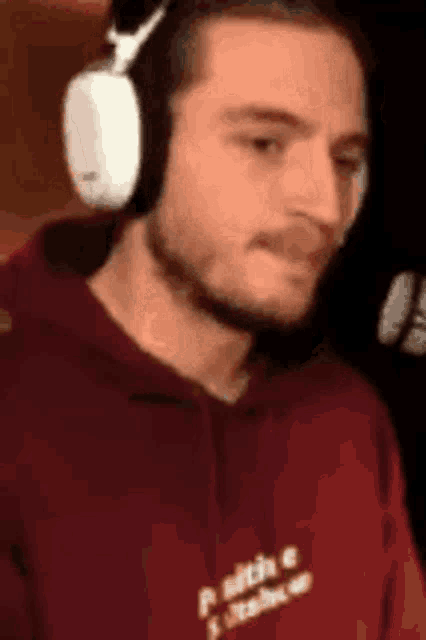 a man wearing headphones and a red hoodie is talking into a microphone .