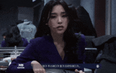 a woman in a purple jacket is looking at herself in the mirror