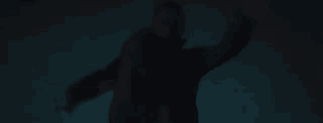 a person is standing in the dark with their hands outstretched .