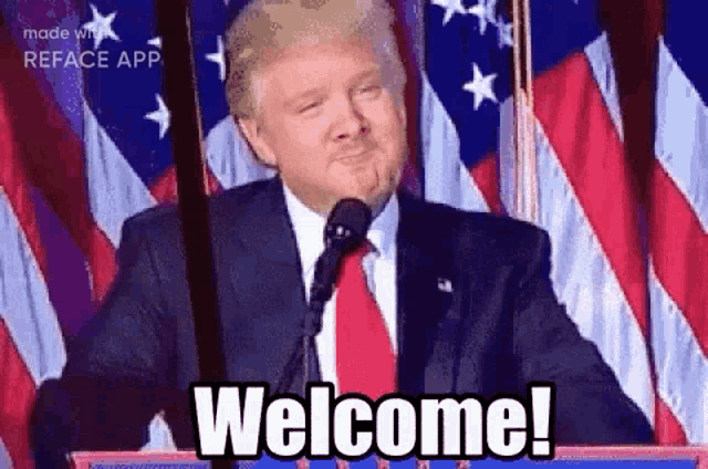 a man in a suit and tie is standing in front of a microphone and saying welcome .