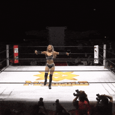 a woman stands in a wrestling ring with the letters mc on the ground