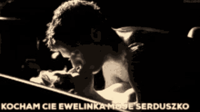 a black and white photo of a man kissing a woman with the words kocham cie ewelinka moje serduszko