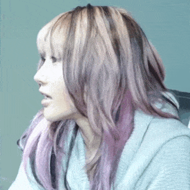 a woman with purple and brown hair is wearing a gray sweater