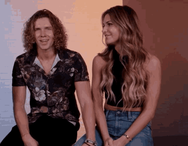 a man in a floral shirt sits next to a woman