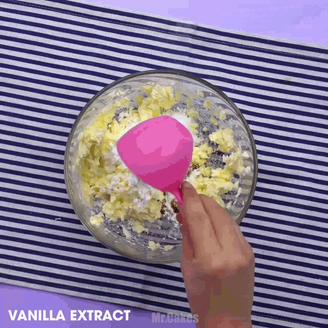 a person pouring vanilla extract into a bowl of butter
