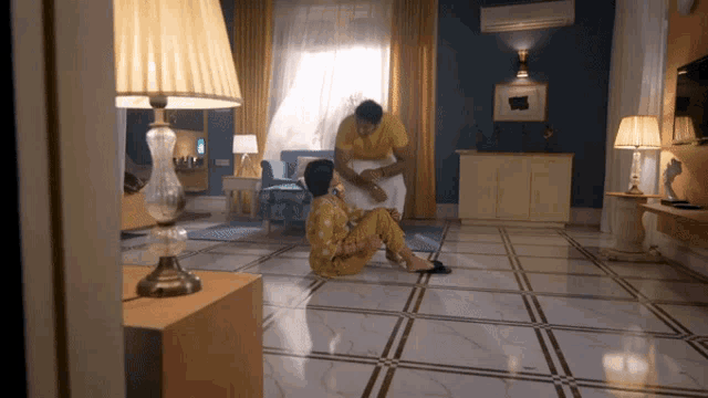 a man in a yellow shirt is helping a woman sit on the floor in a living room