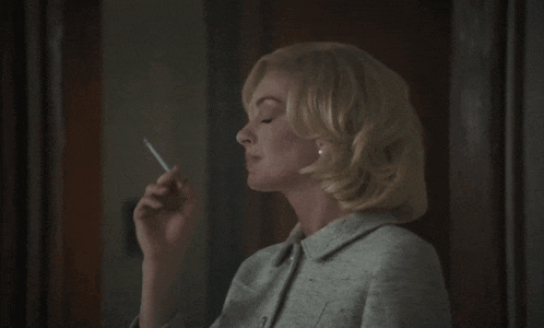 a woman smoking a cigarette in a grey jacket