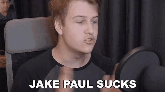 a young man sitting in front of a microphone with the words " jake paul sucks " on the bottom