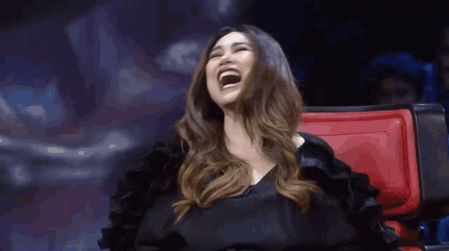 a woman is laughing while sitting in a chair